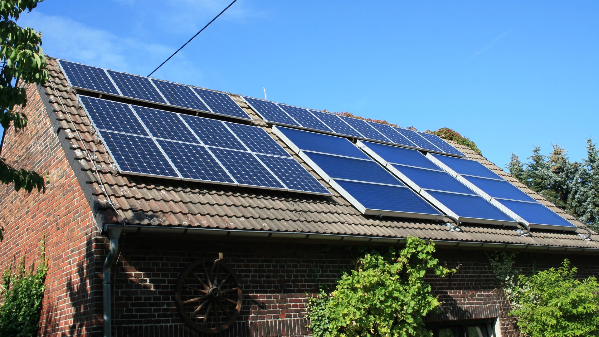 Photovoltaikmodule und Solarthermie-Kollektoren auf dem Dach eines Backsteingebäudes in Selm.